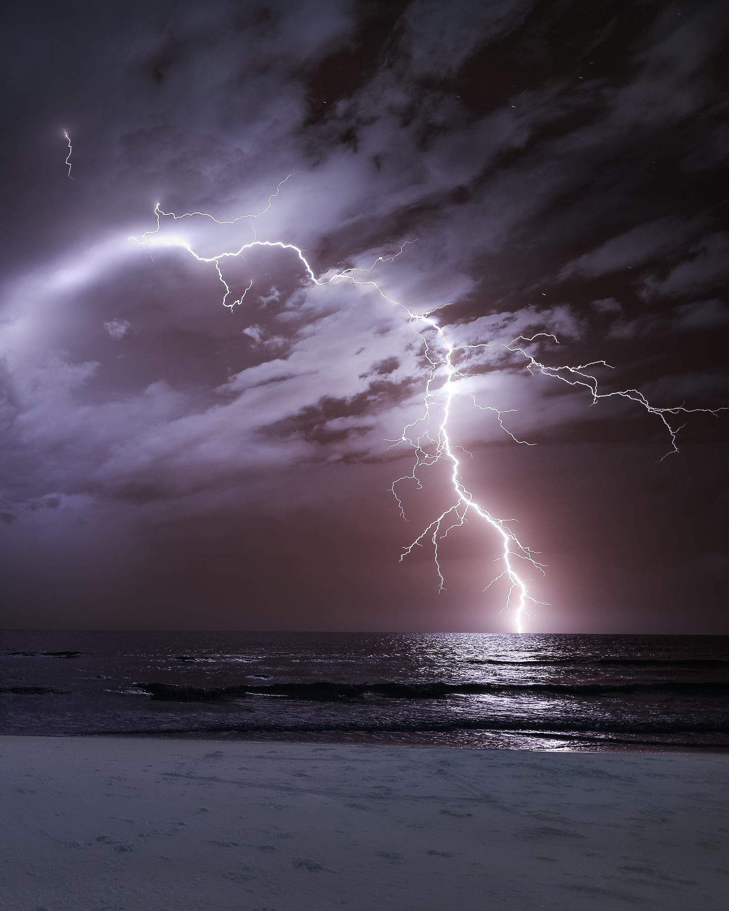 An infrared lightning bolt strikes the Gulf beneath a lavender storm sky — fine art storm photography by Susan Gunn.